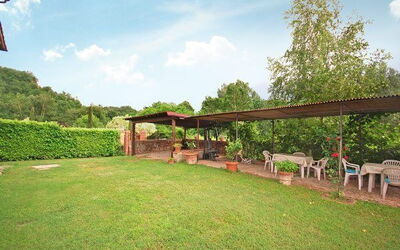 Esclusivo giardino privato di fronte alla casa con un pergolato attrezzato per pranzi all'aperto.